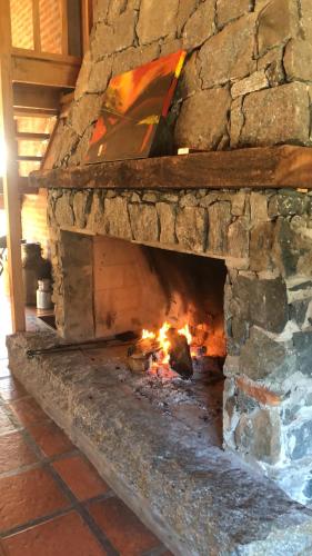 a stone fireplace with a fire in it at Quinta Ecuador Tandil in Tandil