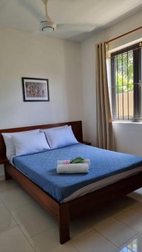 a bedroom with a bed with a blue blanket and a window at Theresa in Trou aux Biches