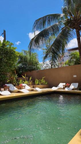 a swimming pool with chairs and a palm tree at Theresa in Trou aux Biches