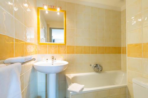 a bathroom with a sink and a tub and a mirror at Europe Hotel Vieux Port in Marseille