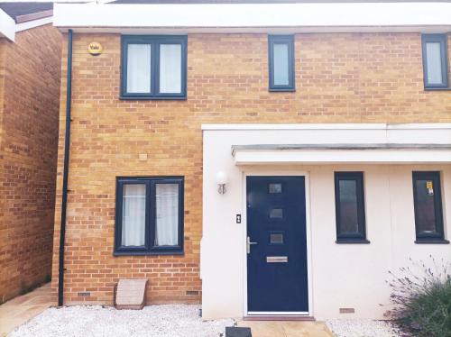 a brick house with a black and white door at Modern home with Netflix, NowTV & 2private parking in East Tilbury