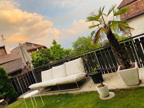 a white couch sitting on a balcony with a palm tree at Magnifique maison avec vue sur lac Léman in Saint-Legier-La Chiesaz