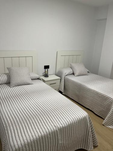 - une chambre avec 2 lits avec des draps rayés dans l'établissement Tía Carmen, Piso familiar en centro Bueu, à Bueu