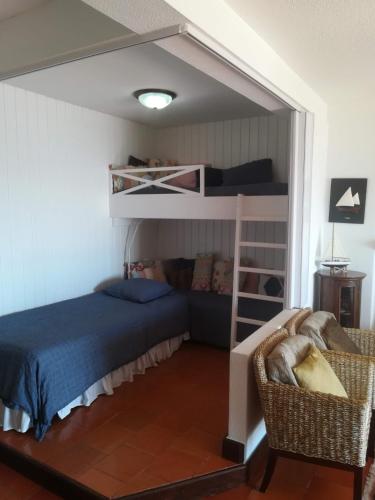 a bedroom with bunk beds and a bed and a chair at Apartment over the Ocean in Sesimbra