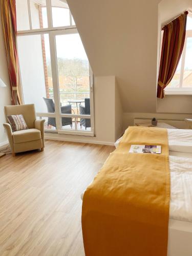 a bedroom with a bed and a chair and a window at Ringhotel Hohe Wacht in Hohwacht