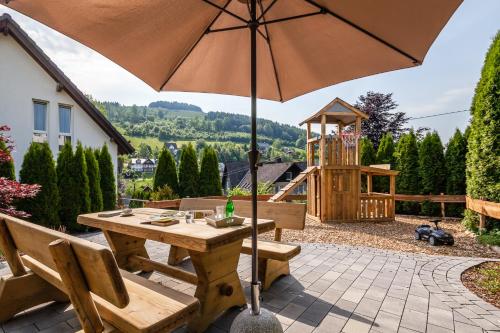 einen Holztisch mit Sonnenschirm auf einer Terrasse in der Unterkunft Ols Berghaus in Olsberg