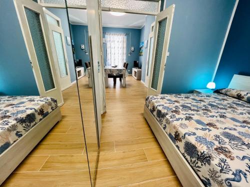 two beds in a room with blue walls and wooden floors at Casa del Pescatore in Isola delle Femmine