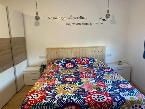 a bed with a colorful comforter in a bedroom at Agradable adosado con zona de aparcamiento in Sedaví
