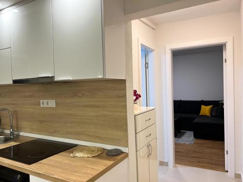 a kitchen with white cabinets and a living room at Apartment Vils Promenade in Sarajevo
