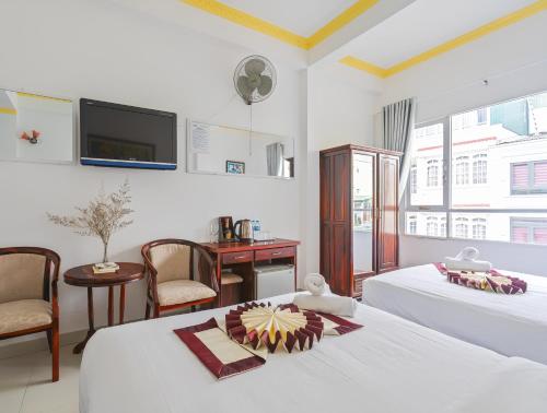 ダラットにあるMiền Nhiệt Đới 2 Hotelのベッドが2つと壁にテレビがある寝室