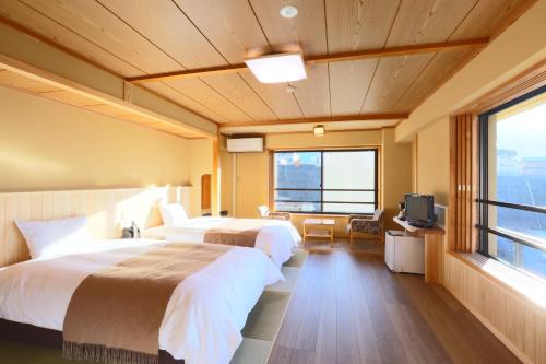 a hotel room with two beds and a television at Shibu Hotel in Yamanouchi