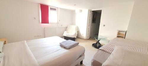 a white bedroom with two beds and a chair at Charmant appartement 2p avec piscine partagée in La Ferté-Gaucher
