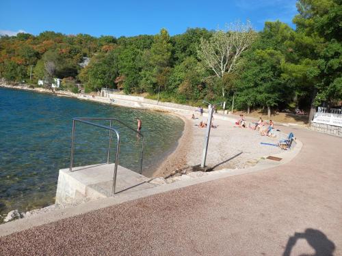 a group of people sitting on a beach next to the water at D,apartman' ulica pušća 51, 51513 Omišalj in Omišalj