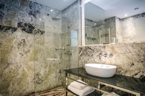 La salle de bains est pourvue d'un lavabo et d'une douche en verre. dans l'établissement Le Palais des Cerisiers, à Azrou