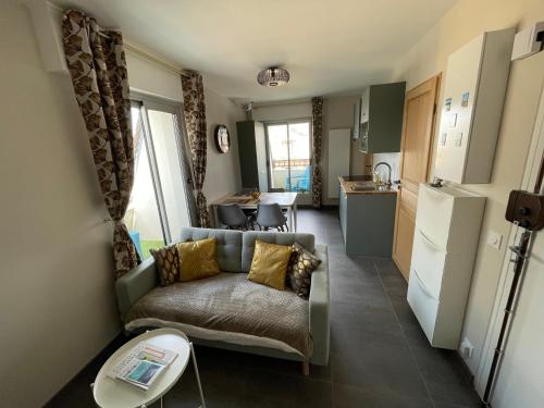 un salon avec un canapé et une cuisine dans l'établissement Les Ormes 17, à Houlgate
