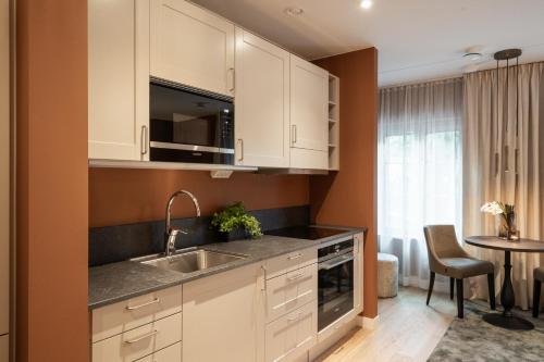 a kitchen with white cabinets and a sink and a table at Live and Stay Ekmanska in Gothenburg