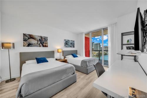 a hotel room with two beds and a table and a desk at Relaxing BeachWalk Getaway Studio for 4 Guests 405B in Hallandale Beach