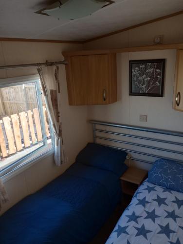 Habitación pequeña con 2 camas y ventana en B58 is a 3 bedroom 8 berth caravan close to the beach on Whitehouse Leisure Park Towyn near Rhyl with private parking space This is a pet free caravan, en Abergele