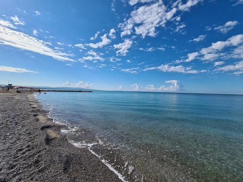 a beach with blue water and a cloudy sky at Hotel La Buca Del Gatto in Marina di Cecina