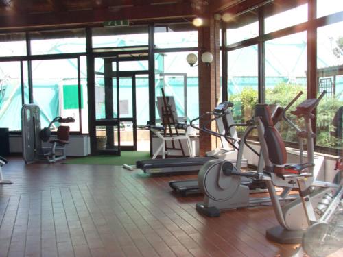 a gym with several cardio machines in a room with windows at Hotel La Buca Del Gatto in Marina di Cecina