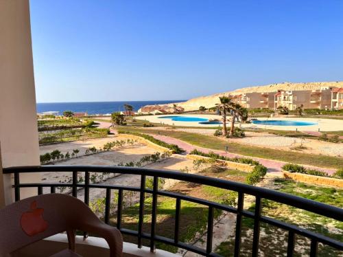 a balcony with a view of the beach and pools at Coral hills North Coast كورال هيلز الساحل الشمالي in Al Dabaa