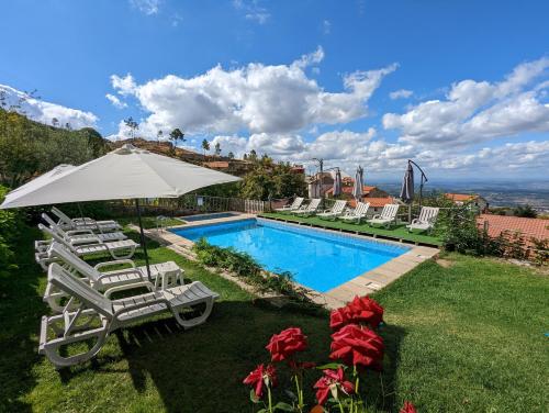 a swimming pool with lounge chairs and an umbrella at Casas do Pastor in Seia