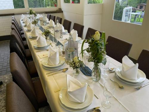 a long table with chairs and white plates and napkins at Hotel Am Wintergarten in Bocholt