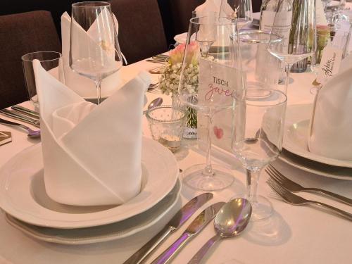 a table with white plates and wine glasses and napkins at Hotel Am Wintergarten in Bocholt
