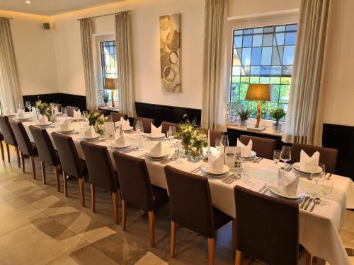 a conference room with a long table with white tables and chairs at Hotel Am Wintergarten in Bocholt