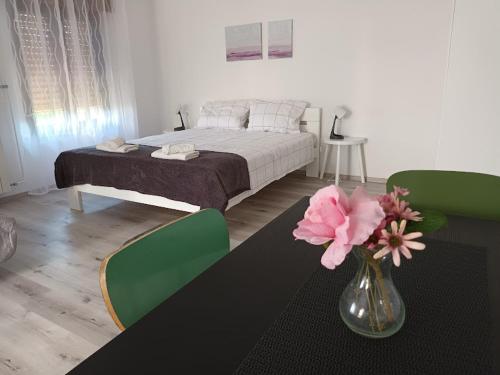 - une chambre avec un lit et un vase avec des fleurs sur une table dans l'établissement Apartma ODDIH, à Dutovlje