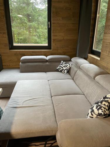 a living room with a large couch and two windows at Chalet FiMiLi in Vyšná Boca