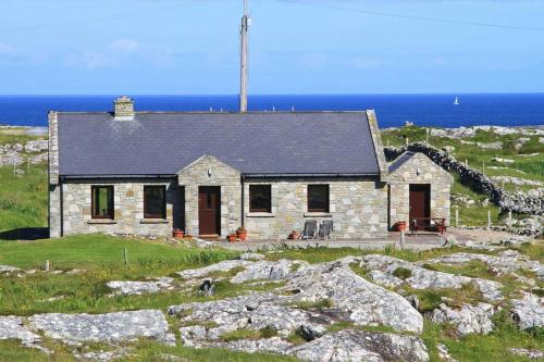 a stone house on a hill near the ocean at Luxury Sea View Cottage Ballyconneely Winter Specials in Ballyconneely