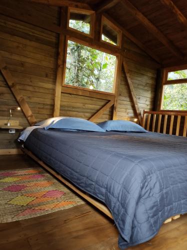 a large bed in a log cabin with windows at La Cabaña de Huckleberry in El Retiro