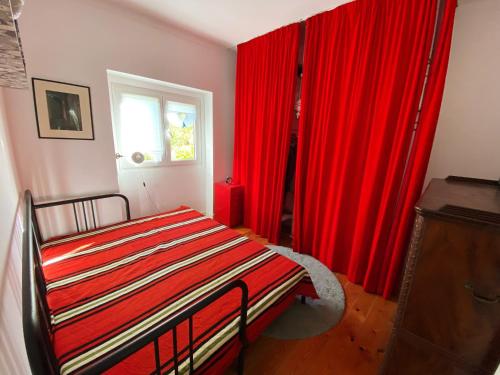 um quarto com cortinas vermelhas, uma cama e uma janela em Casa das Boganvilias - Moradia com jardim em Lisboa