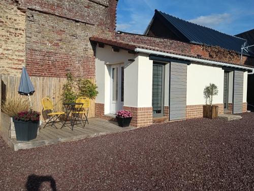 a patio with a table and chairs next to a brick building at Le cabanon in Méneslies