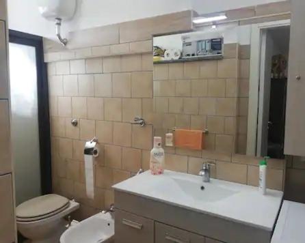 een badkamer met een wastafel, een toilet en een spiegel bij Piano terra casa intera (no smoking!!!!) in Qualiano