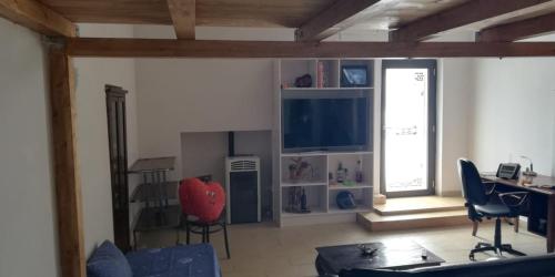 een woonkamer met een tv, een bureau en stoelen bij Piano terra casa intera (no smoking!!!!) in Qualiano