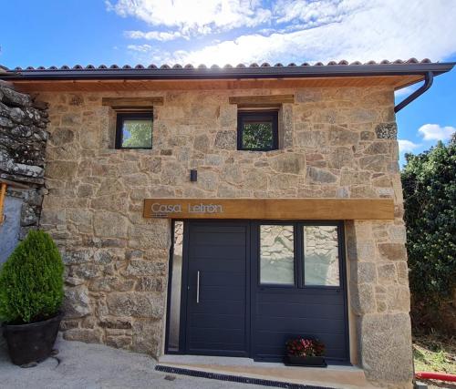 a stone house with a blue garage door at Casa Leirón in Parada del Sil