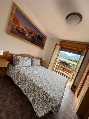 a bedroom with a bed and a large window at Dolomitihouse AVET in Fiera di Primiero