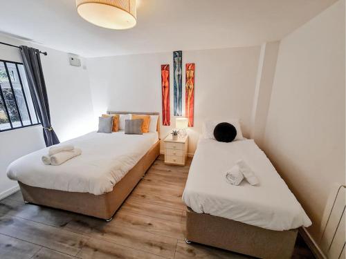a bedroom with two beds and a window at Comfy 2 bed Flat with free Parking, close to Tube in Woolwich