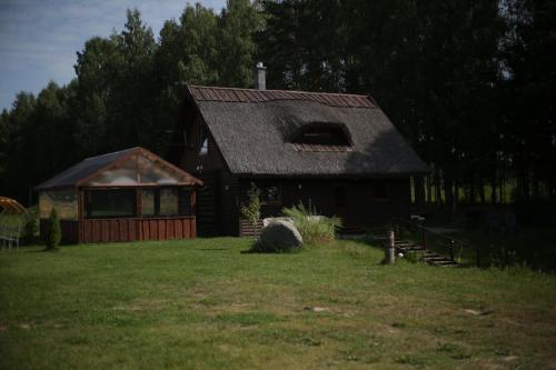 a small house with a gambrel roof on a yard at Pirts māja Ramatas in Skulte