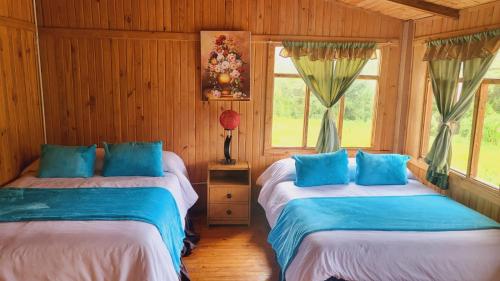 two beds in a room with wooden walls and windows at Mindo GlamBird Glamping & Lodge in Mindo