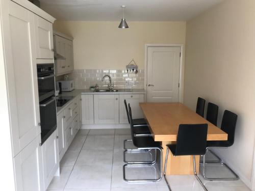 a kitchen with a wooden table and black chairs at Modern 3-bedroom townhouse in the Mournes in Newry