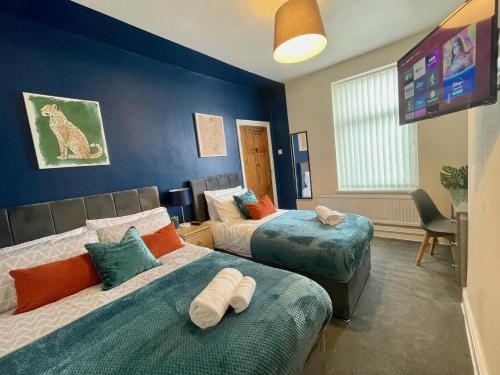 a hotel room with two beds and a tv at Kimberworth House, 4 Bedrooms, WIFI, Close to M1, Longer Stay, Free Parking in Rotherham
