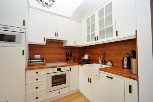 a white kitchen with white cabinets and a sink at Apartmán Hrebienok, Vysoké Tatry in Smokovce