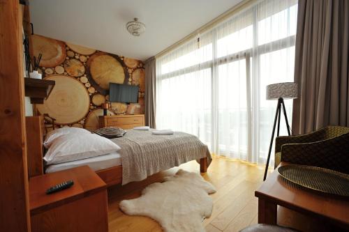 a bedroom with a bed and a large window at Apartmán Hrebienok, Vysoké Tatry in Smokovce