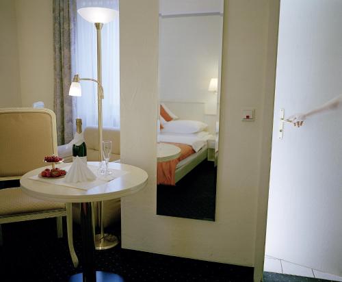 Habitación con mesa, cama y espejo. en Hotel Dalberg, en Aschaffenburg