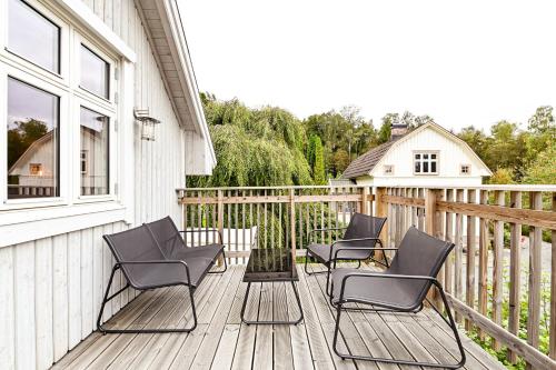 a porch with four chairs on a wooden deck at Nyhagens trädgård och B&B in Berghem