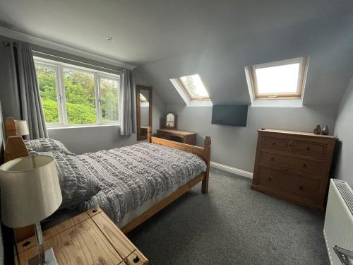 a bedroom with a bed and a dresser and windows at Brae Hoose in Arisaig