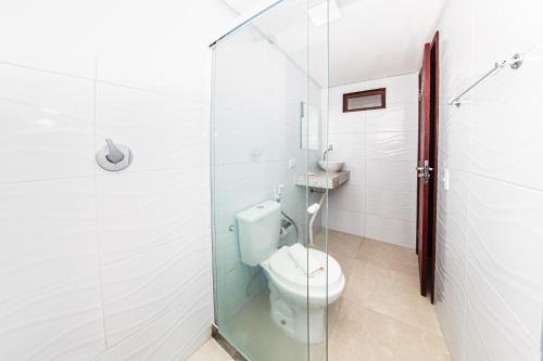 a bathroom with a toilet and a glass shower at Pousada Maanaim Porto in Porto De Galinhas